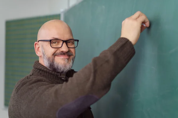 Веселий вчитель пише на зеленій дошці — стокове фото