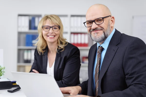 Grinning professionals sitting together at table — Stock Photo, Image