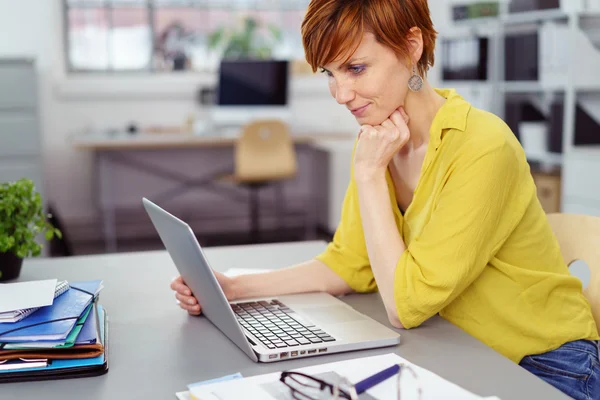 Empresária atenciosa na mesa com laptop — Fotografia de Stock