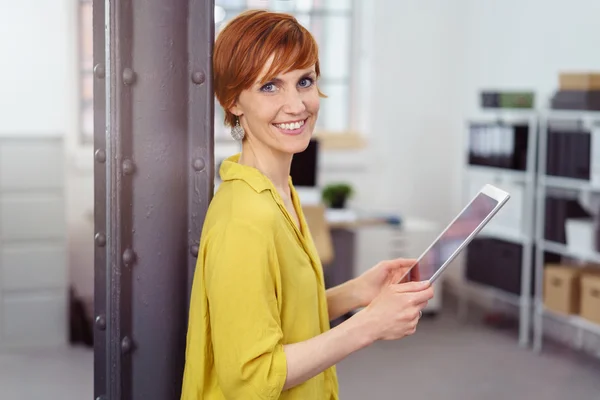 Smiling female business owner leans against beam