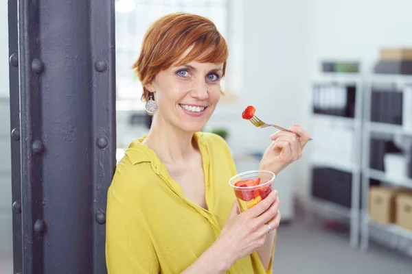 Smal grinande kvinna äta från en frukt mellanmål cup — Stockfoto