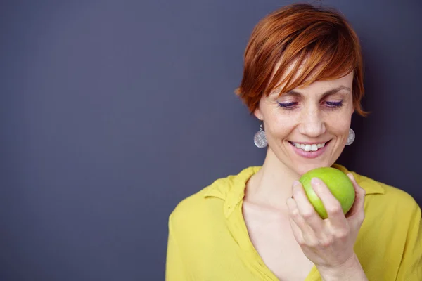 Pretty young woman looking at a fresh apple — Stock Photo, Image