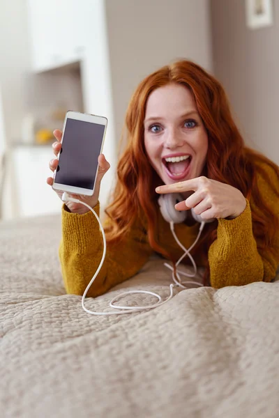 Jovem excitada apontando para seu celular — Fotografia de Stock