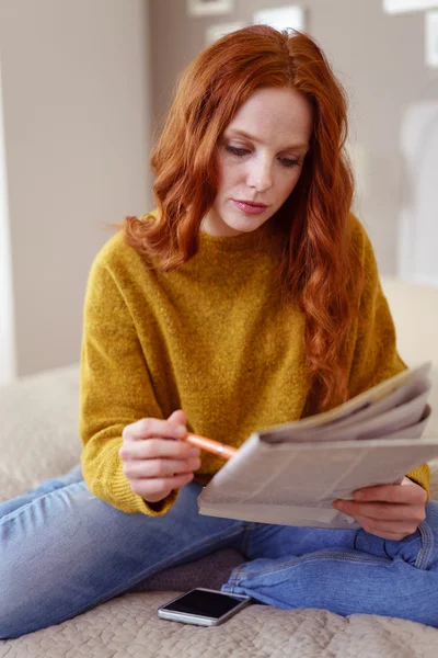 Seriös kvinna i tröja tittar på tidningen — Stockfoto