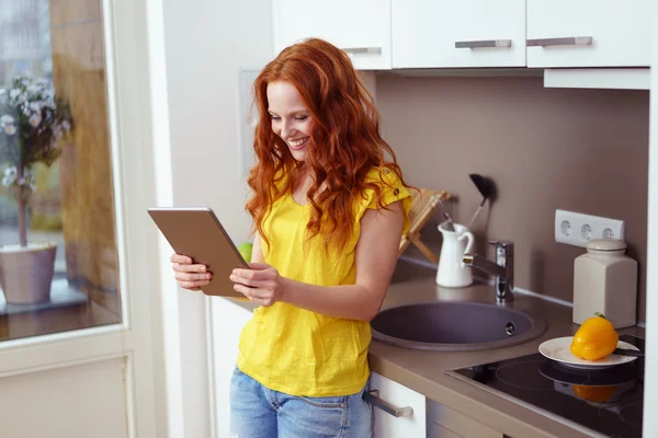 Ευτυχισμένος ενήλικος γυναίκα χρησιμοποιώντας tablet υπολογιστή στην κουζίνα — Φωτογραφία Αρχείου