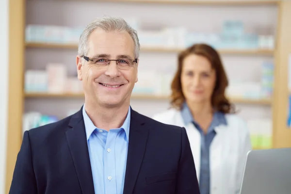 Smiling business man at drug store counter — Stock Photo, Image