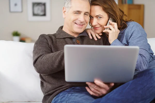 Wife holds phone to ear while seated by husband — Stock fotografie