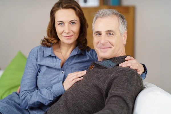 Grinning middle aged couple together on sofa — Stock Photo, Image