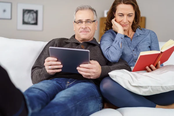Distracted mature handsome couple seated on couch — Stock Photo, Image
