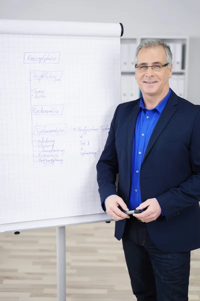 Confident businessman next to chart in office — Zdjęcie stockowe