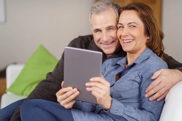 Handsome mature couple seated on couch with tablet — Stock Photo, Image