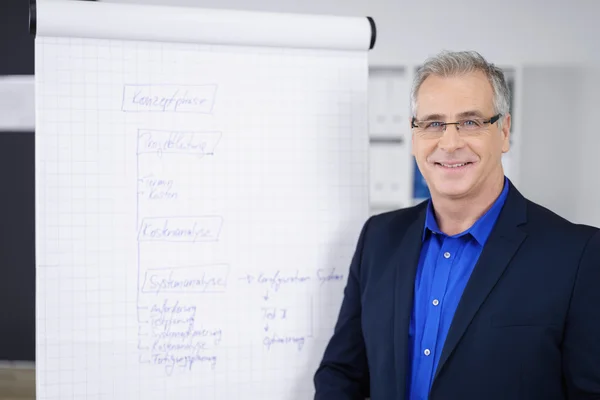 Smiling business executive man next to chart — Stock Photo, Image