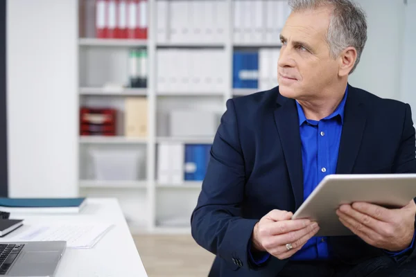 Empresário atencioso sentado segurando um tablet — Fotografia de Stock