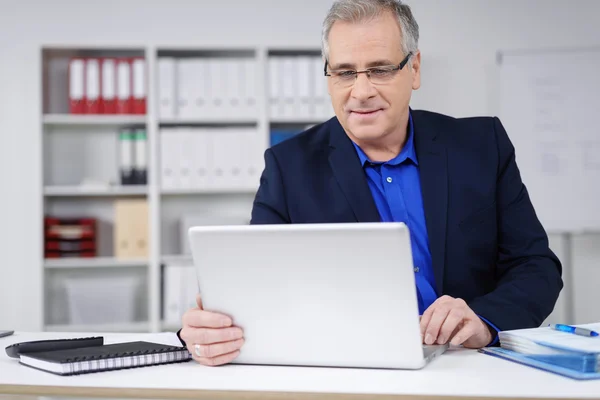 Empresário atraente trabalhando em um laptop — Fotografia de Stock