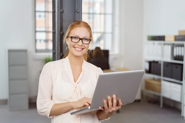 Empresária sorridente com laptop no escritório — Fotografia de Stock