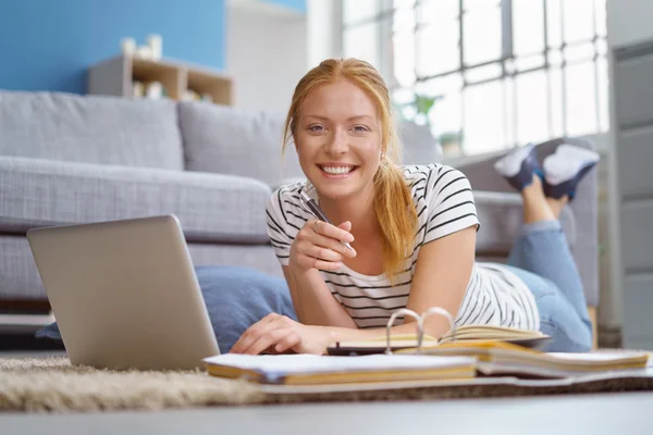 Smiling woman relaxing at home with a laptop