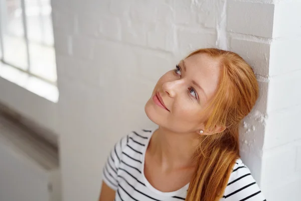 Young red haired woman in striped shirt looks up — Stok fotoğraf