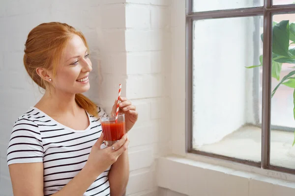 Glückliche Frau mit Karottensaft am Fenster — Stockfoto