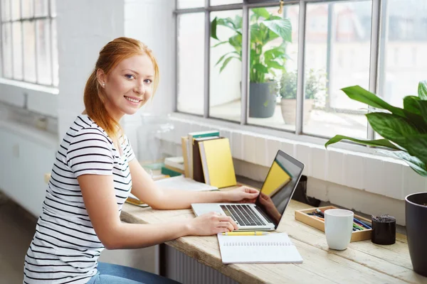 Giovane donna seduta a lavorare a un tavolo — Foto Stock