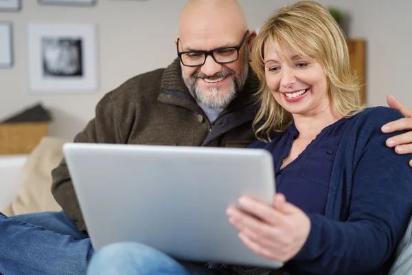 Upphetsad par sittande på soffan i vardagsrummet — Stockfoto