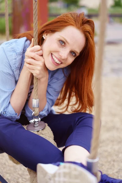 Prachtige jonge vrouw zittend op schommel buitenshuis — Stockfoto