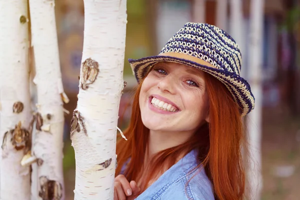 Cute red haired woman in hat beside birch trees — Stock Photo, Image