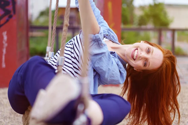 Zorgeloze jonge vrouw spelen op een touwschommel — Stockfoto