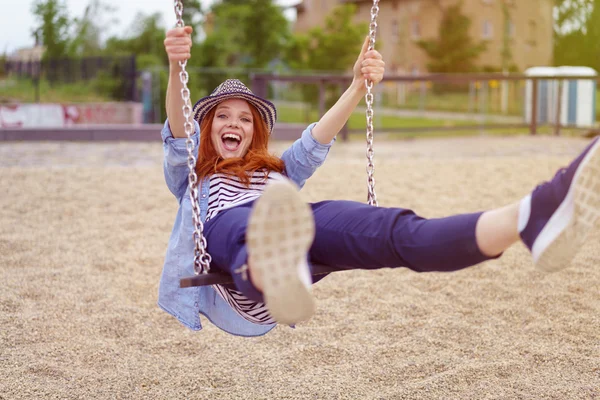 Femme heureuse riant alors qu'elle joue sur une balançoire — Photo