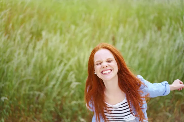 Lekfull ung kvinna plaskar i ett vårfält — Stockfoto