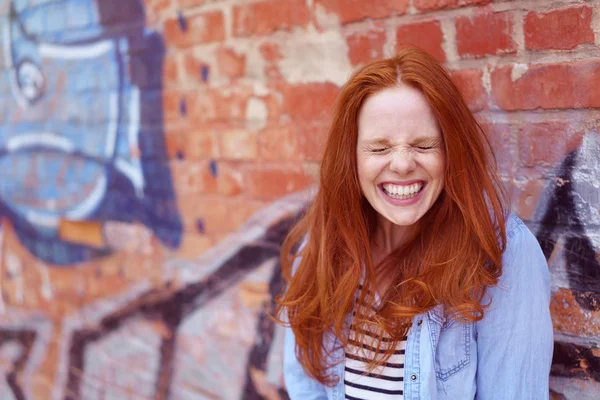 Laughing cute young woman next to brick wall — Stock Photo, Image