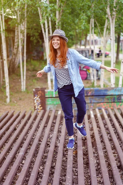 Playful woman balancing on a wooden slatted deck — Stock Photo, Image