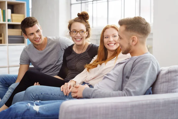 Discusión entre cuatro amigos sentados en el sofá — Foto de Stock