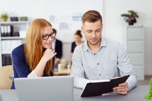 Hombre y mujer mirando las notas en el trabajo — Foto de Stock