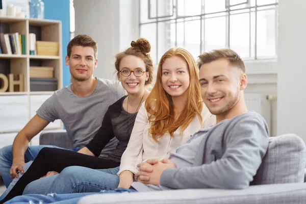 Relaxing seated friends smile at camera in room — Stock Photo, Image