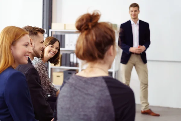 Mujer sonriente escuchando a su compañero de trabajo durante la reunión — Foto de Stock