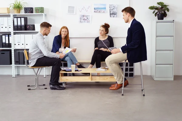 Група з чотирьох молодих людей, які сидять в маленькому офісі — стокове фото