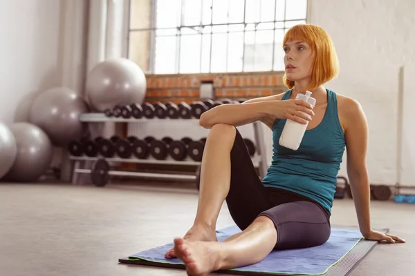 Young woman pausing to drink water in a gym — 图库照片