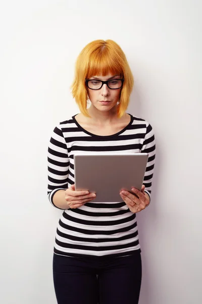 Mujer pelirroja joven seria leyendo en su tableta — Foto de Stock