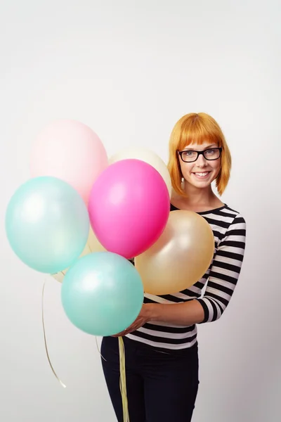 Donna sorridente che tiene un mucchio di palloncini da festa — Foto Stock