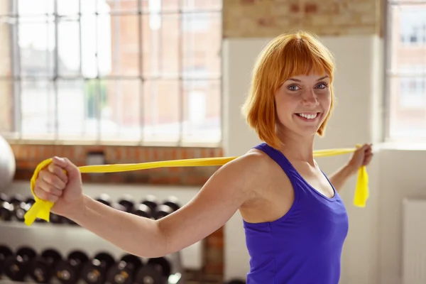 L'atleta dalla testa rossa tiene la fascia elastica gialla — Foto Stock