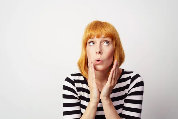 Surprised woman with red hair places hands by face — Stock Photo, Image