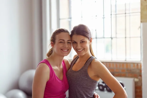 Twee gelukkige glimlachende jonge vrouwen in een sportschool — Stockfoto