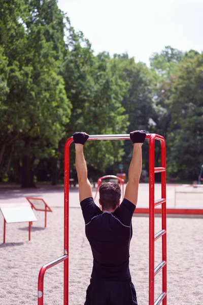 Young man working out on a bar outdoors — Stock Photo, Image