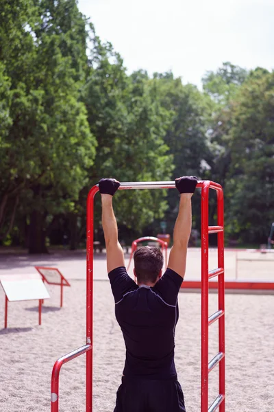 Young man working out on a bar outdoors — Stockfoto