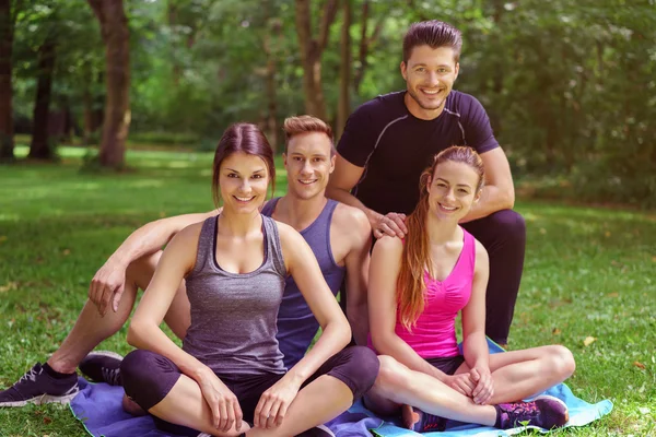 Small smiling group of athletes sits together — Stock Photo, Image