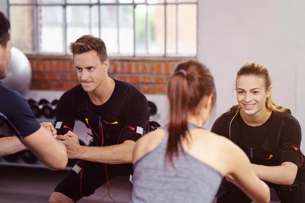 Четыре улыбающихся спортсмена сидят на корточках во время тренировки — стоковое фото