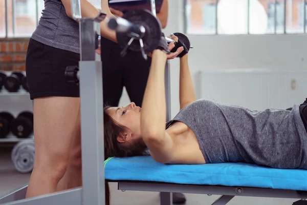 Instructor helping a young woman lifting weights — Stock Photo, Image