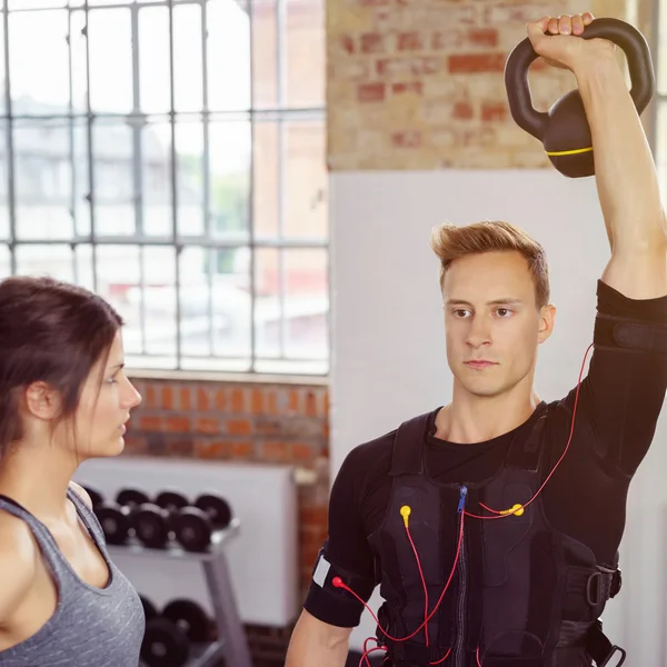 Trainer helpen man in biometrische vest lift gewichten — Stockfoto