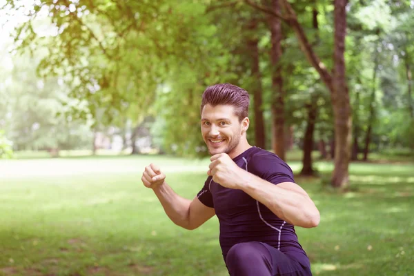 Glimlachend gelukkig jonge man met zijn vuisten verhoogd — Stockfoto