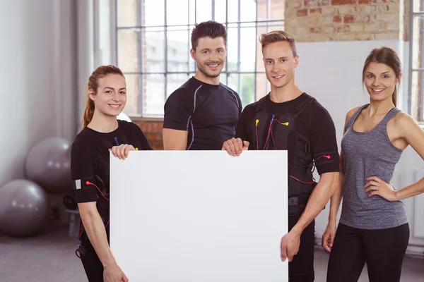 Fitness team in a gym holding a blank sign